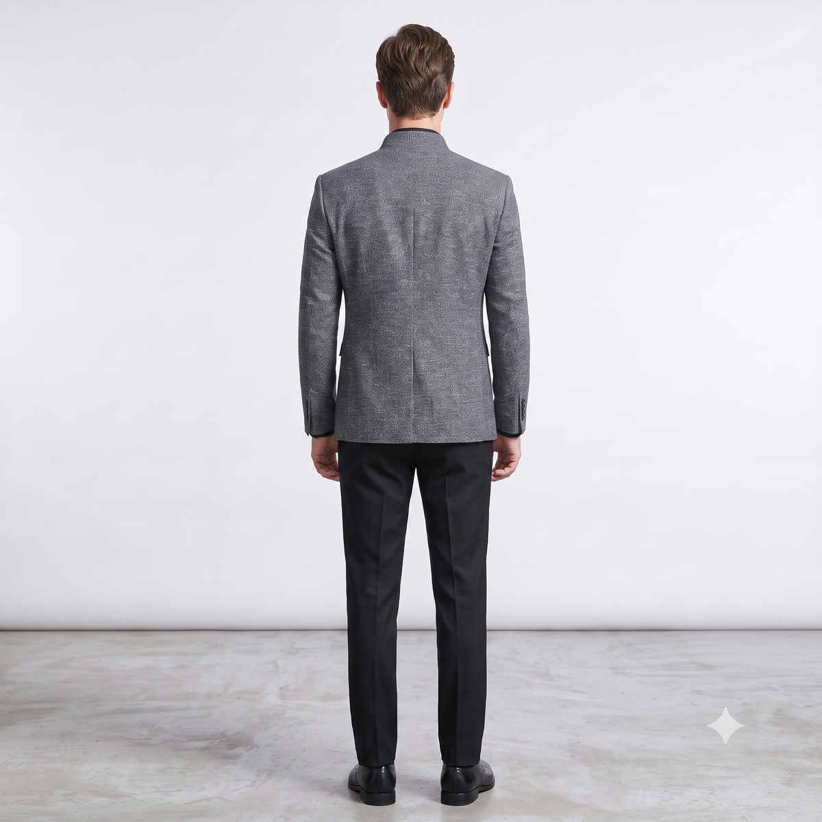 Man wearing a gray blazer and black pants on a white background
