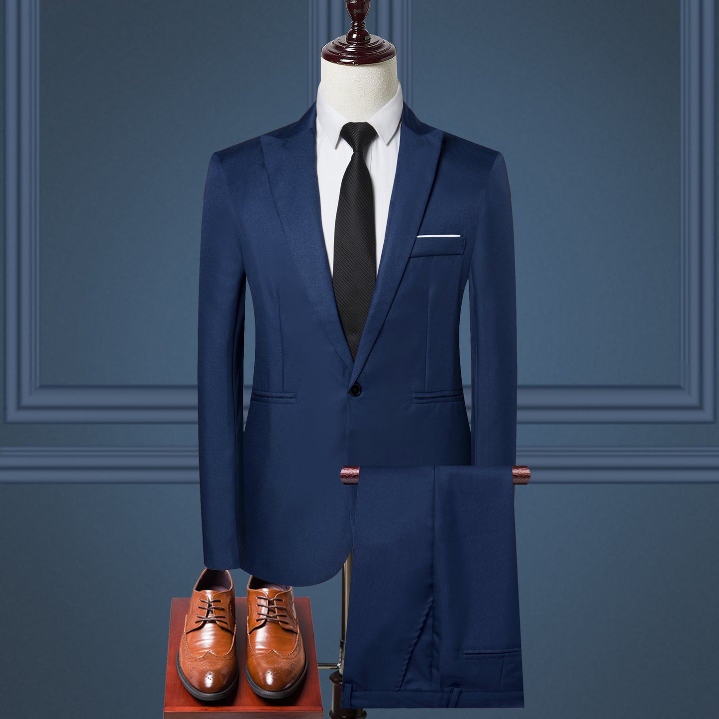 Blue suit on a mannequin with brown shoes in front of a blue wall.
