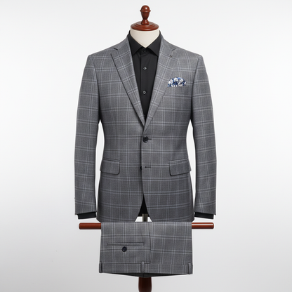 Two-piece grey checkered men’s suit displayed upright on a wooden stand. Slim-fit jacket with structured shoulders and two-button closure, paired with matching trousers folded neatly over the display bar. Styled with a black dress shirt and patterned pocket square. Clean studio background with soft, even lighting. ratio 250:250